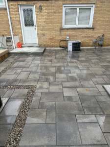 Lumen Landscaping | Interlock Grey interlock patio at a back door with a pea gravel inlay strip, yellow brick house, Hamilton Mountain