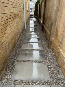Lumen Landscaping | Ice on the Walkway Every Winter Side yard walkway of large grey slabs set in gravel beside a brick house on Hamilton Mountain