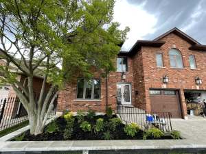Lumen Landscaping | Hamilton New raised garden bed with a grey stone wall and fresh plantings in front of a brick house in Stoney Creek