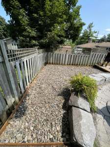 Lumen Landscaping | Water Pooling in the Yard River rock bed with wood edging and natural stone slabs beside a flagstone path in Vineland