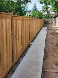 Lumen Landscaping | Muddy Side Yard New wood privacy fence along a side yard with a fresh concrete walkway