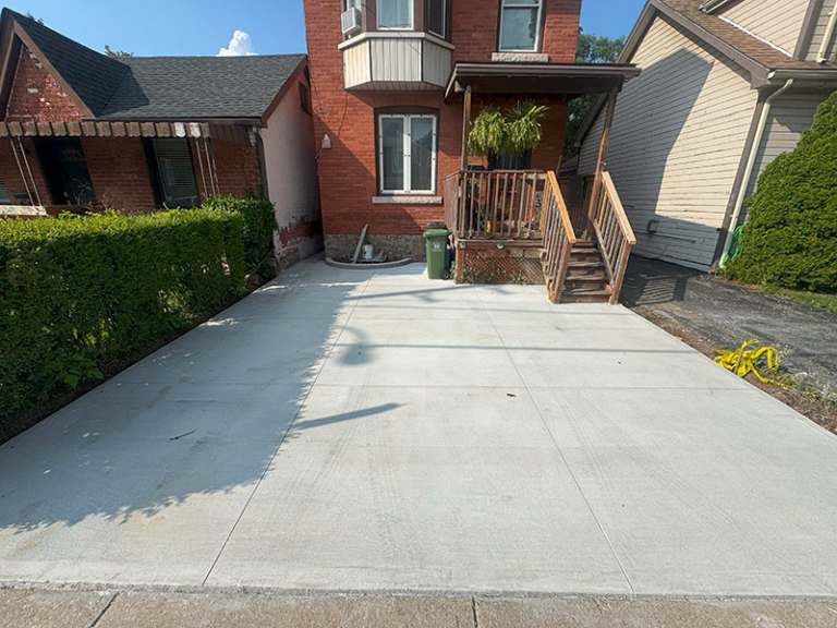 Lumen Landscaping | Home Landscaping New broom finish concrete driveway running up to the steps of a brick house