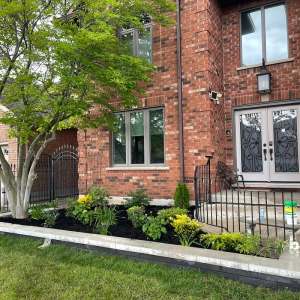 Lumen Landscaping | Clay Soil: Nothing Grows Front garden bed with new shrubs in black mulch edged by light grey stone caps
