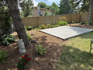 Lumen Landscaping | Cracked Concrete Steps and Porch New grey concrete pad in a backyard beside mulch beds, hostas and a tree