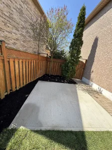 Lumen Landscaping | Cracked Concrete Steps and Porch New plain concrete pad in a fenced side yard with black mulch beds
