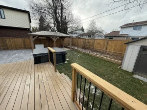 Lumen Landscaping | Service Areas Wood deck overlooking a pavilion over a hot tub, an interlock patio and a fenced lawn