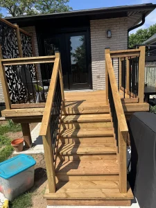 Lumen Landscaping | Fences and Gates Wood deck stairs with black balusters and decorative privacy panels at a back door
