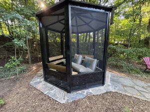 Lumen Landscaping | Flamborough Black screened gazebo with cushioned seating on an irregular flagstone pad among trees