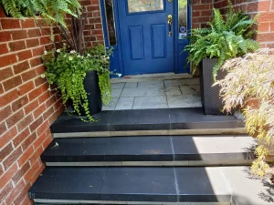 Front steps slab treads planters Front steps with large slab treads and landing, framed by planters