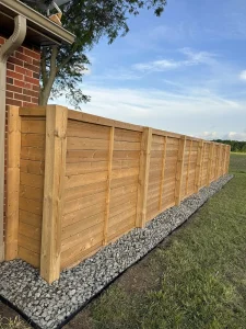 Lumen Landscaping | Fences and Gates Horizontal wood privacy fence with a grey gravel strip along its base