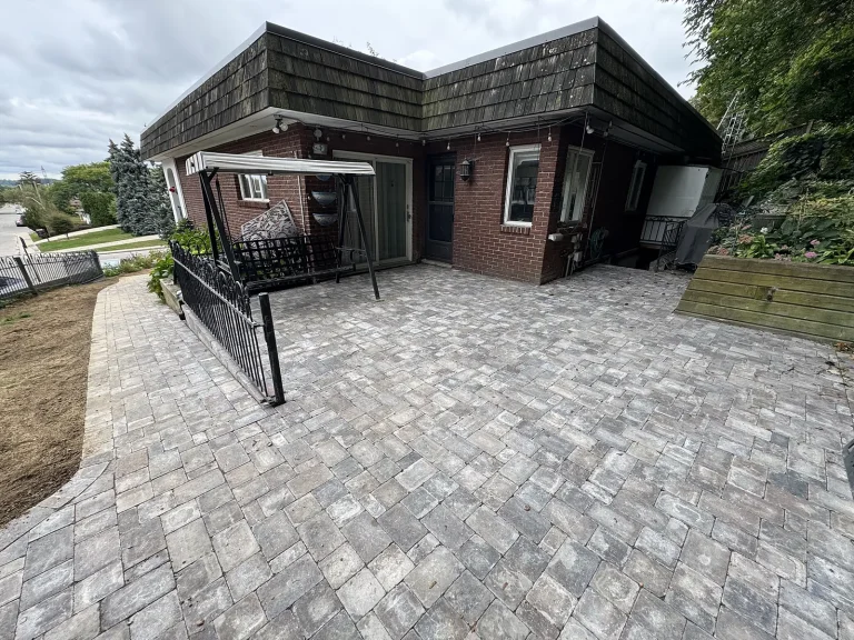 Lumen Landscaping | Home Landscaping Large grey interlock patio wrapping around the back of a brick home