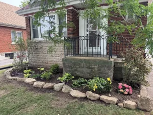 Natural stone border front garden Front garden bed edged with natural stone and planted with perennials and hydrangeas
