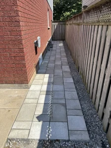 Lumen Landscaping | Interlock Side yard slab walkway with a gravel drainage border along the fence